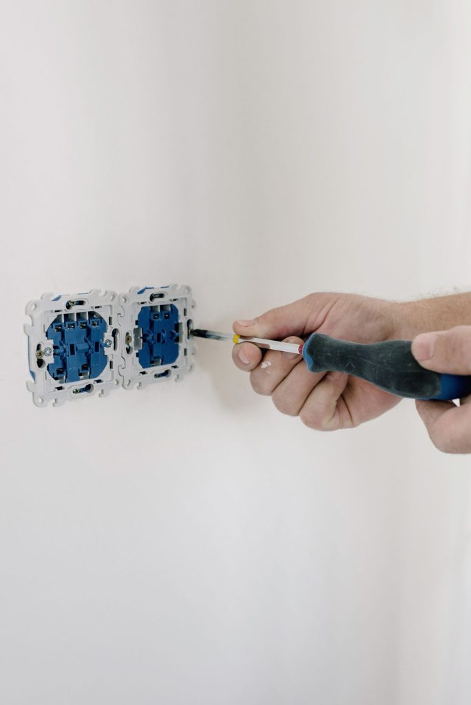 Electrician fitting a new light switch with a screwdriver