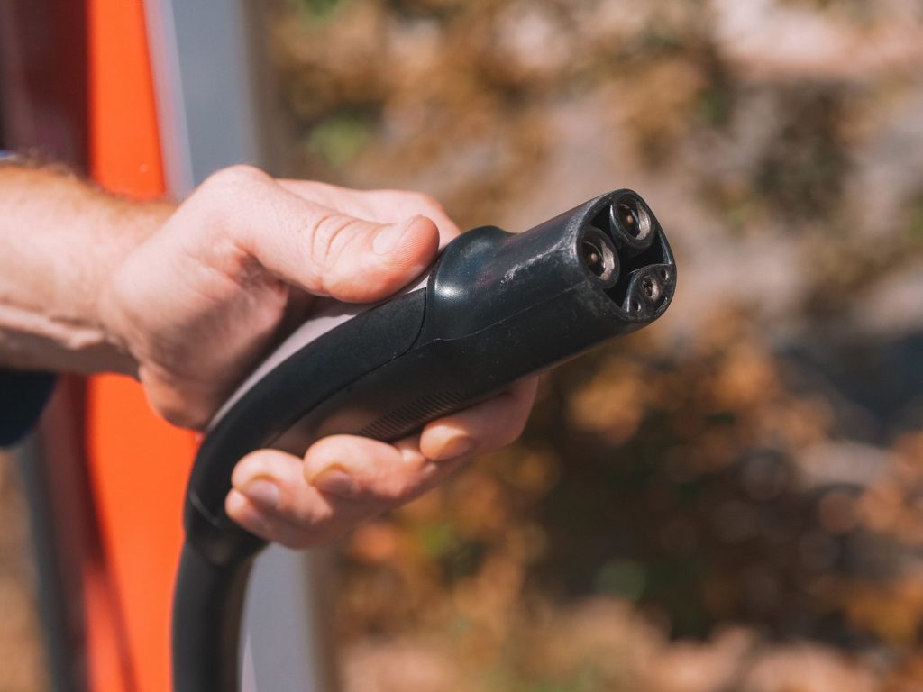 Hand holding an EV charging plug ready to connect