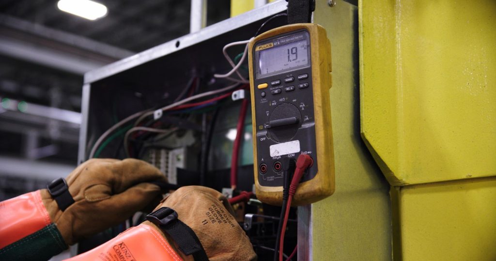 Electrician measuring voltage on control wiring with a multimeter