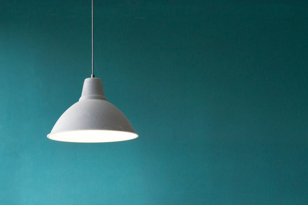 White pendant lamp hanging against a teal wall